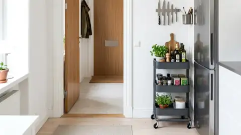 Interior estilo escandinavo funcional aprovechando huecos muertos con estanterías blancas y carritos auxiliares